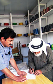 Mohamad the tent-maker in Madaba signing the deal, with Romel Gharib watching